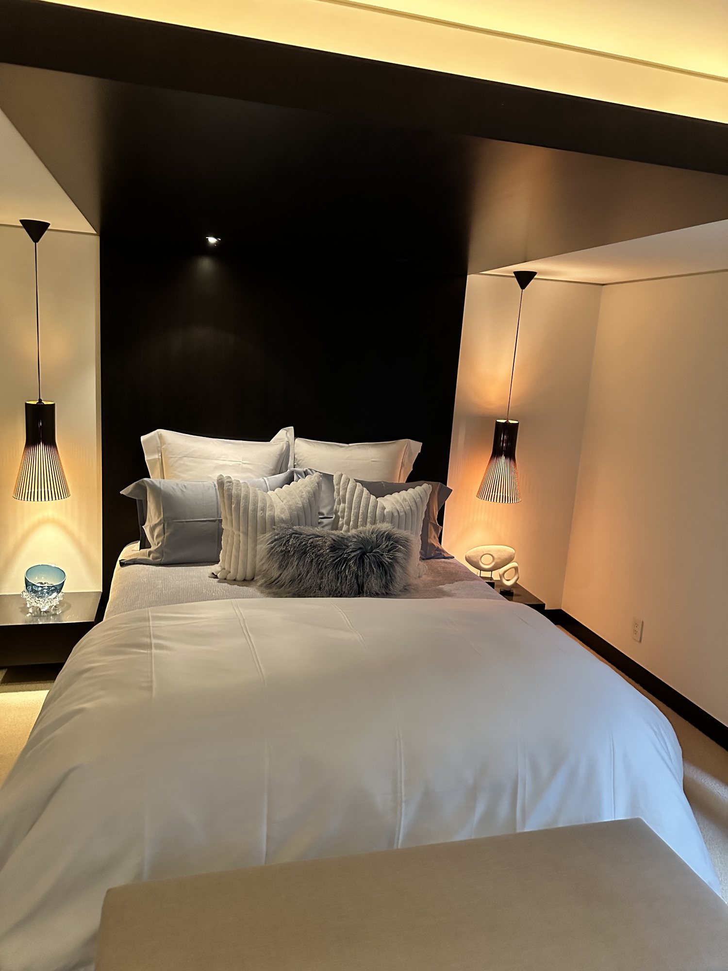 Dark editorial bedroom with pendant lighting and layered bedding
